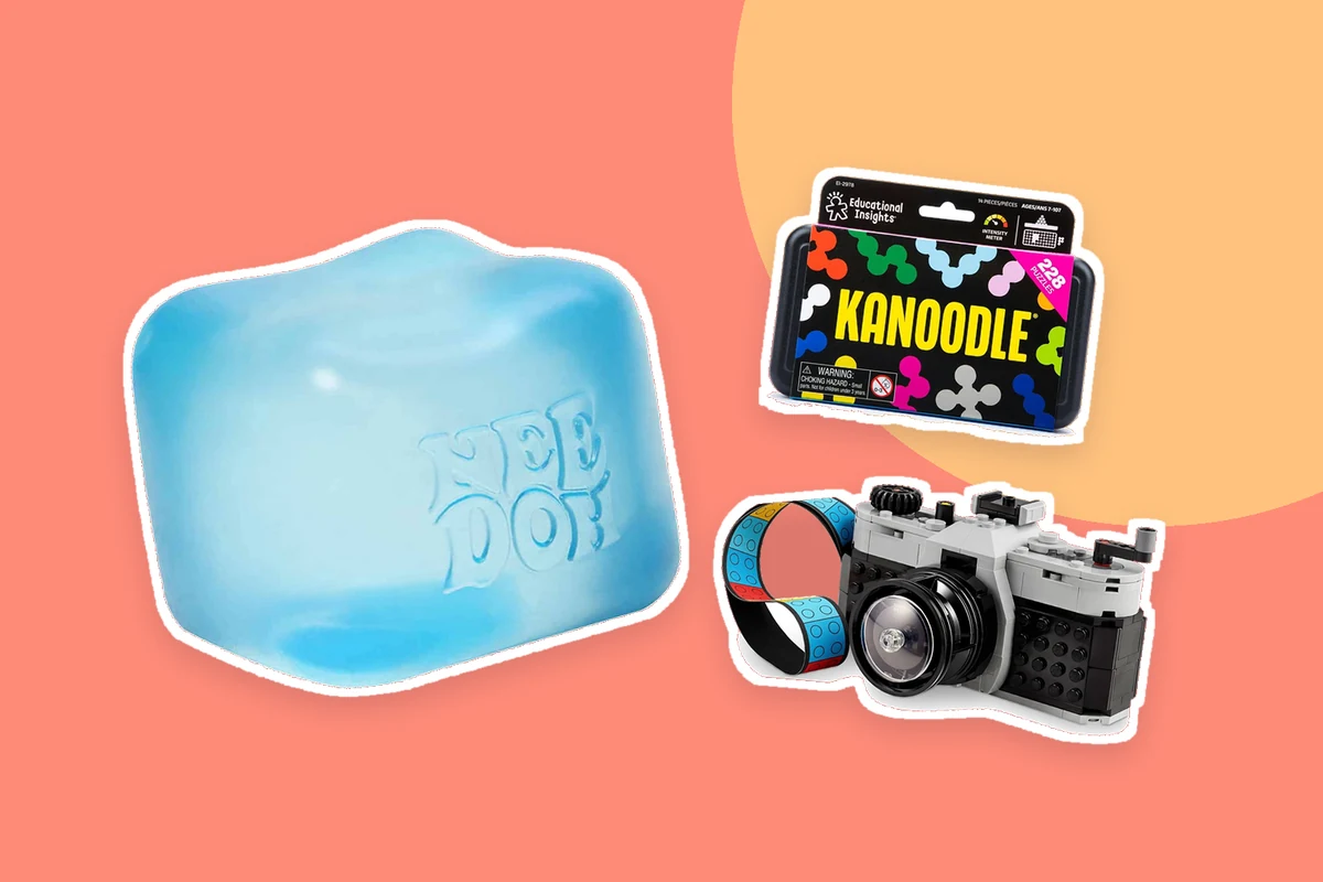 Real product photographs of a blue NeeDoh Nice Cube, a Kanoodle puzzle and a LEGO Retro Camera on a bright coral background