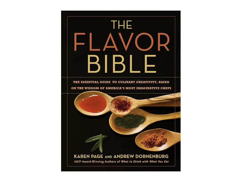 The black cover of The Flavor Bible by Karen Page and Andrew Dornenburg, with wooden spoons holding colorful spices
