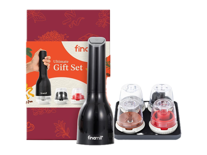 A black FinaMill grinder beside four clear spice pods on a dark tray, with the burgundy and orange Ultimate Gift Set box