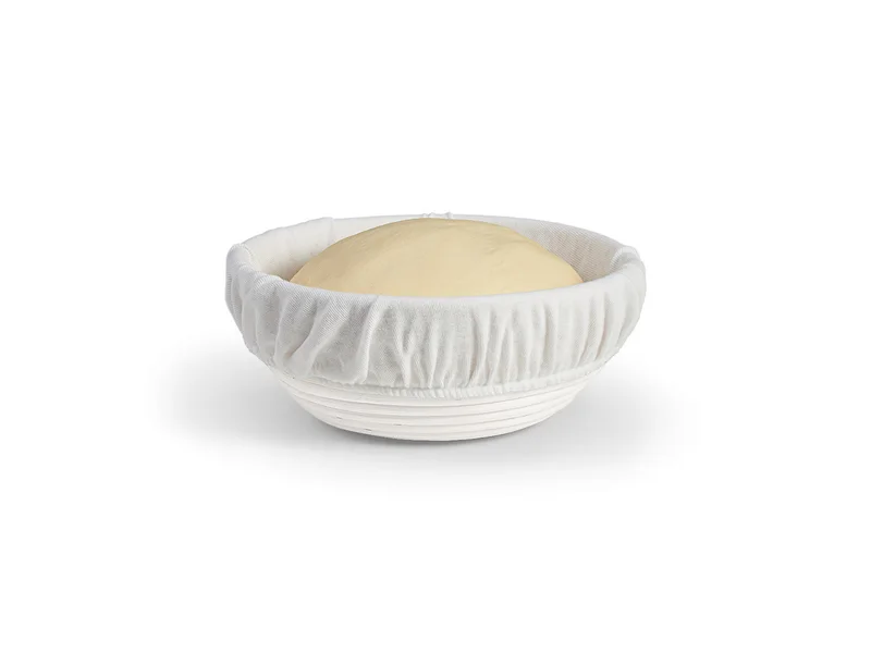 Round bread proofing basket with a cream cotton liner holding dough