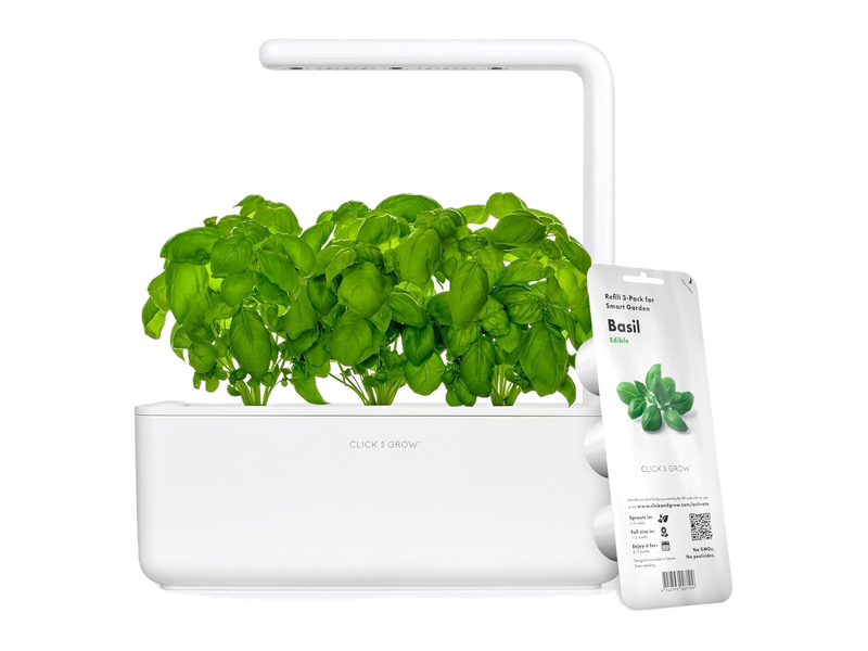 A white Click and Grow Smart Garden 3 shown with mature basil, an overhead light and a basil pod packet